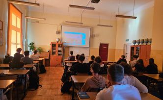 Sala lekcyjna (geografia) z ławkami, przy których siedzą uczniowie.