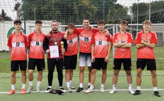 8 uczniów w sportowych strojach na boisku sportowym