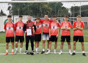 Ośmioro chłopców w sportowych strojach na boisku sportowym