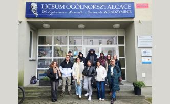 Grupa uczniów i dorosłych przed drzwiami liceum.