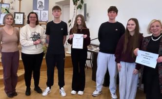 Kilka osób stojących razem z dyplomami w auli szkoły