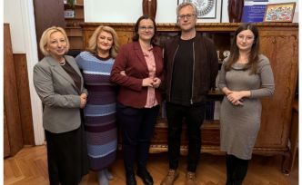 Pięć osób pozuje do wspólnego zdjęcia na tle drewnianej szafki.