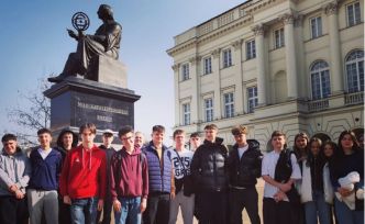Grupa młodzieży pozuje do zdjęcia przed Pomnikiem Kopernika w Warszawie.