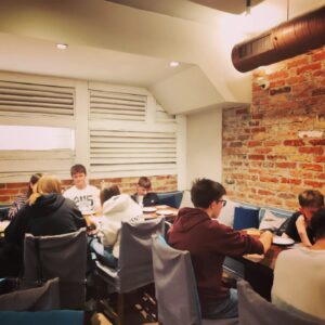 Grupa młodzieży siedzi przy stole w restauracji. 