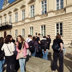 Grupa młodzieży stoi na ulicy Warszawy. 