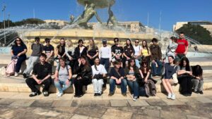 Grupa uczniów pozuje do zdjęcia na tle pomnika.