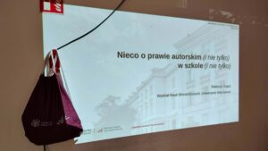 Widok slajdu z prezentacji i plecaka z Wydziału Nauk Ekonomicznych UW.