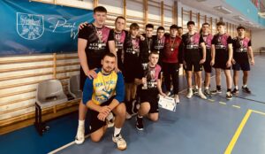 Zespół chłopców w strojach sportowych prezentujący medale i dyplom po zawodach.