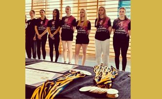 Zespół dziewcząt w strojach sportowych. Na stole medale i dyplomy.