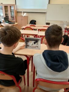 Uczniowie siedzą w klasie lekcyjnej.