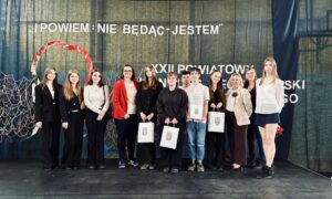 Uczestnicy i opiekunowie konkursu stoją na tle ściany z napisem Zespół Szkół w tłuszczu,  patrząc w stronę aparatu.