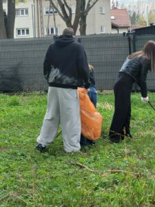 Dwoje uczniów zbiera śmieci z trawnika. 