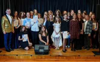 Duża grupa młodych osób prezentująca dyplomy podczas zdjęcia grupowego.