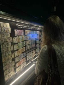 Osoba patrząca na wystawę z banknotami.