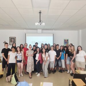Zdjęcie grupowe na tle ściany ze slajdem z napisem ERASMUS+